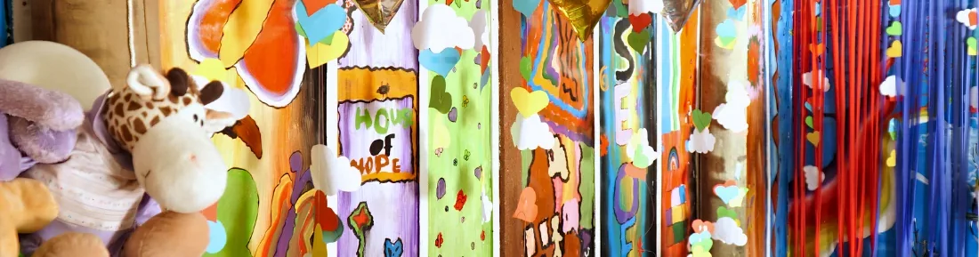 Classroom pillars painted by the children with hearts, clouds and flowers, soft toys on a shelf alongside